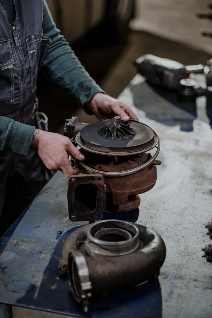 Home Mechanic working on a turbocharger assembly in a repair shop setting.